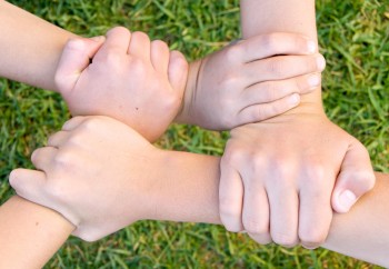 children's hands clasped together to form the shape of a square with their linked wrists